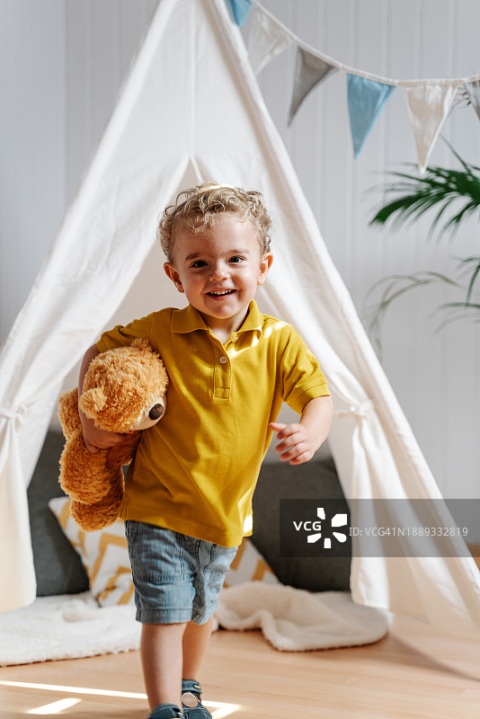 小男孩在家中儿童房玩泰迪熊图片素材