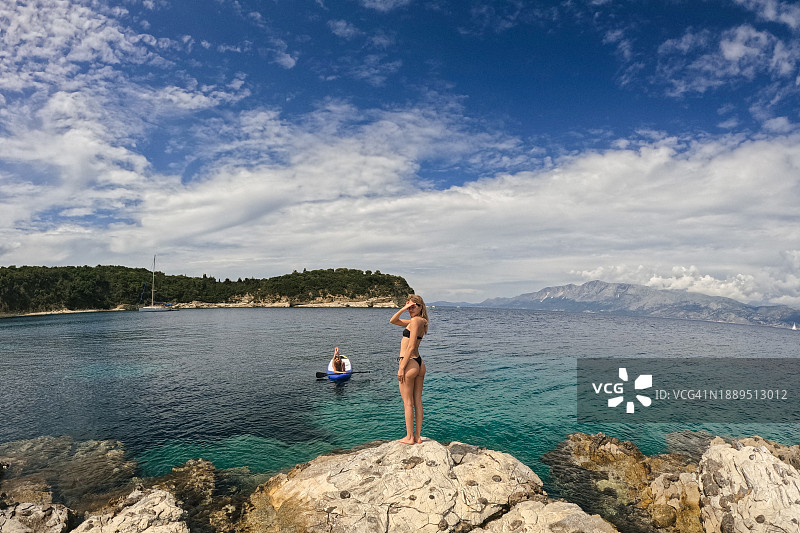 站在海边岩石上的年轻女人图片素材