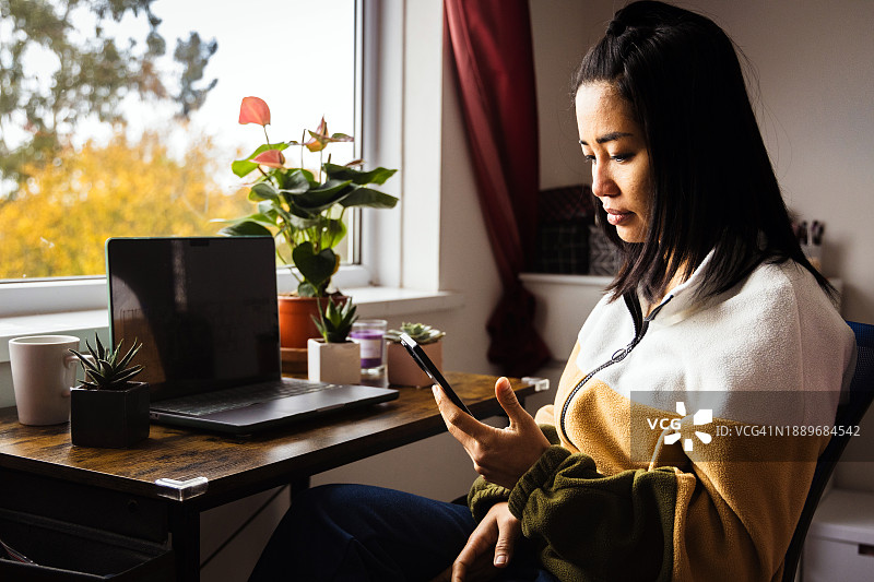 在临时家庭办公室用笔记本电脑远程办公的年轻女子图片素材