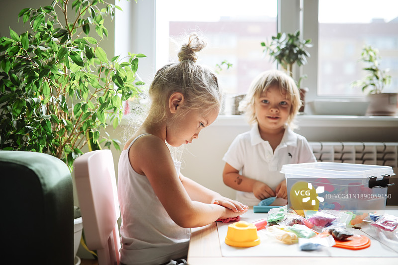 兄妹情深：姐姐和弟弟在家里的桌子上一起用橡皮泥制作图片素材