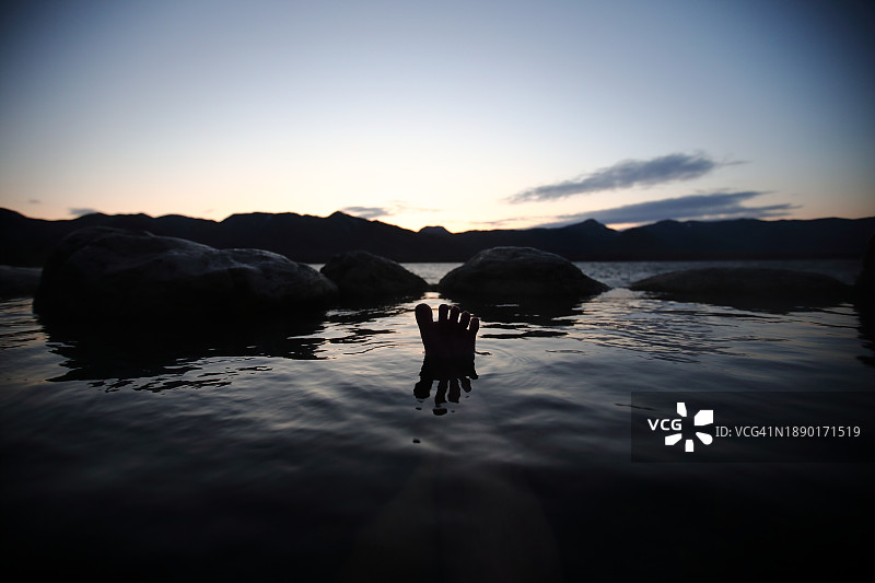 黄昏时分在日本露天温泉中人脚在水中的倒影图片素材