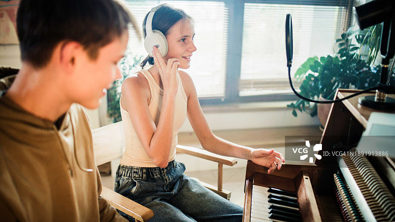 女学生练习唱歌，男学生在钢琴上弹奏嘻哈音乐图片素材