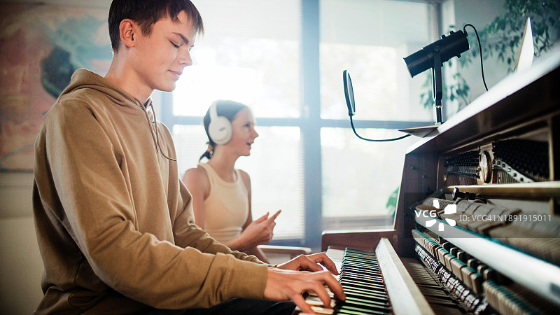 女学生练习唱歌，男学生用钢琴伴奏图片素材