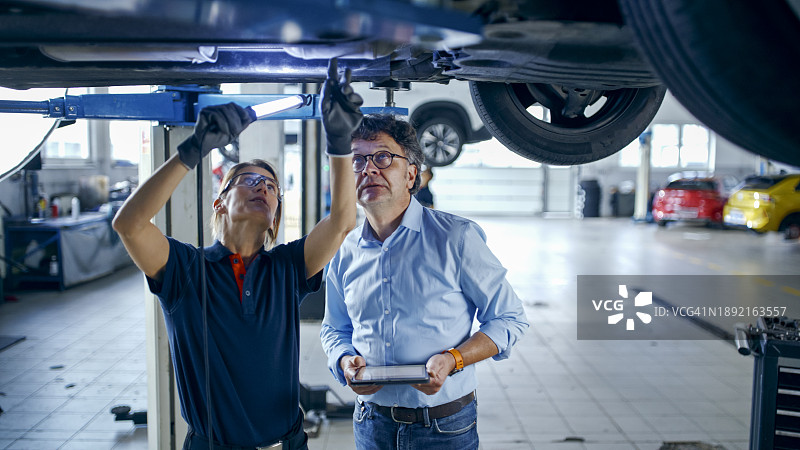 女机械师和经理在车间讨论汽车维修图片素材