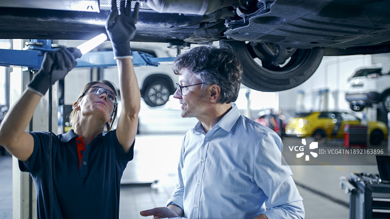 女机械师和经理在车间讨论汽车维修图片素材
