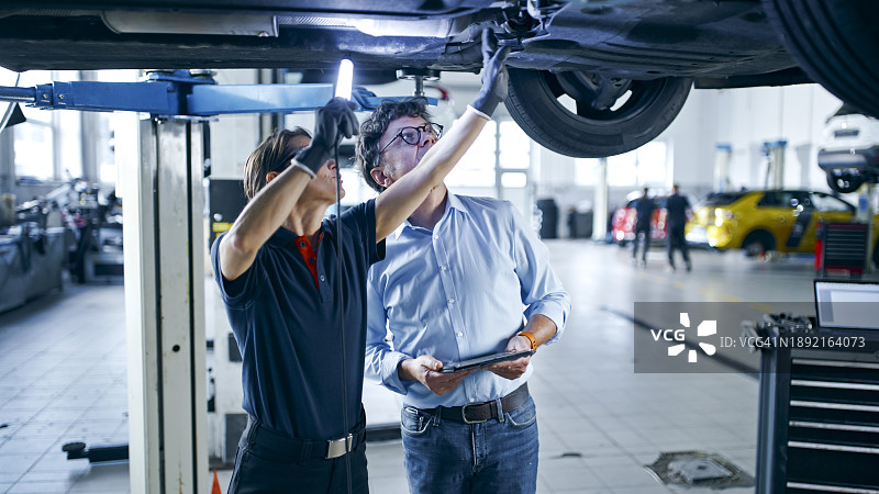女机械师和经理在车间讨论汽车维修图片素材