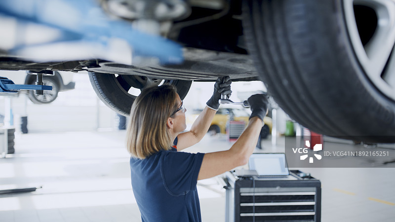 在汽车修理店修理汽车底盘的女修理工图片素材