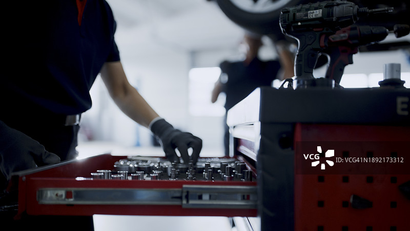 在汽车修理店工具箱抽屉里寻找工具的女机修工图片素材