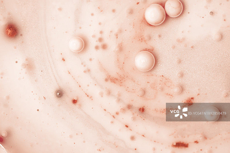 2024年流行色蜜桃色展示：具有复制空间的抽象背景，油、牛奶和水，表面气泡形成的天然纹理背景，护肤美容产品纹理图片素材
