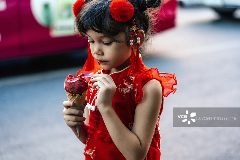 穿着中国传统服装吃冰淇淋的可爱小女孩图片素材