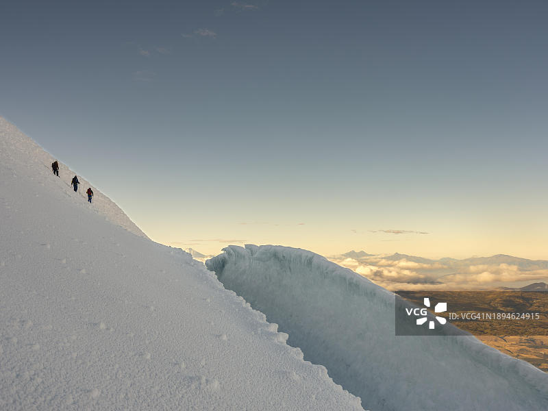 登山者在卡扬贝火山陡峭冰川的裂缝上方，厄瓜多尔皮钦查省卡扬贝图片素材