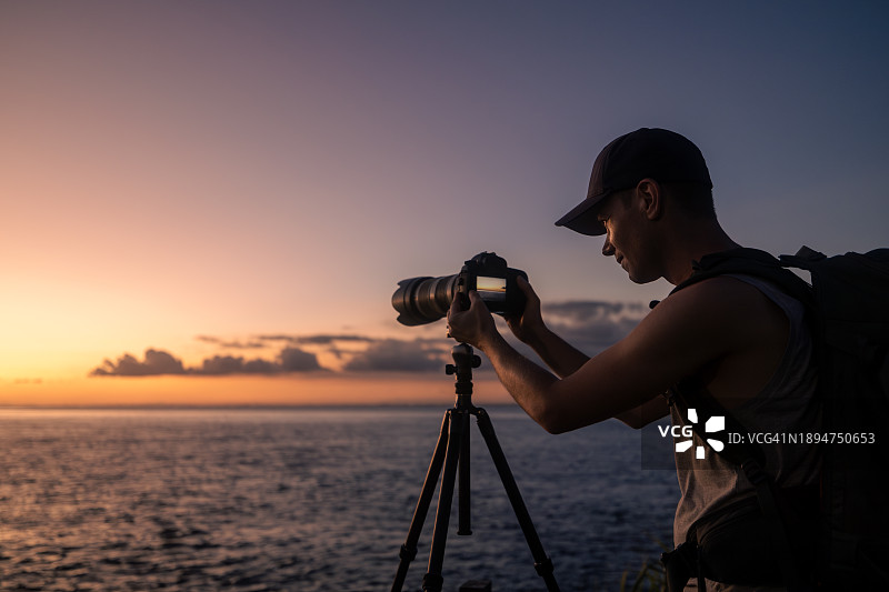 摄影师用三脚架上的相机拍摄日落图片素材