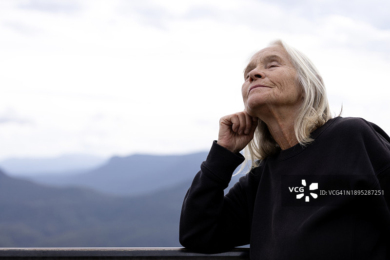 闭着眼睛在户外做梦的老年妇女肖像，背景留白图片素材