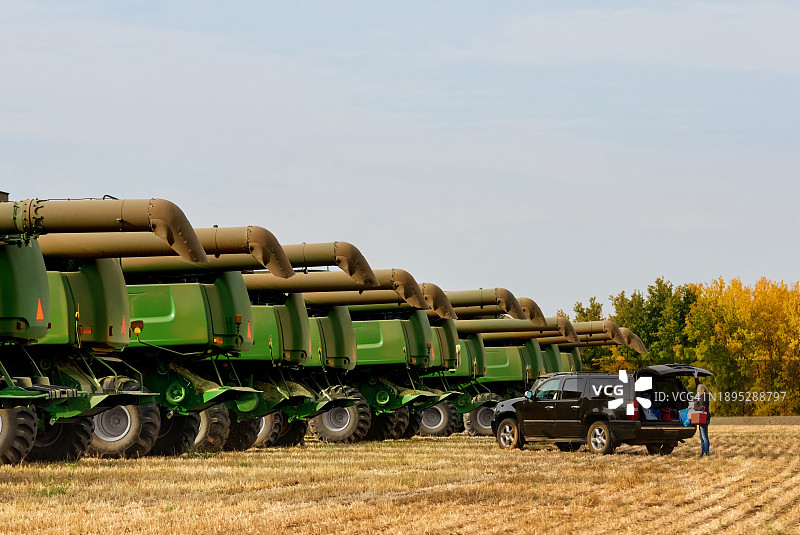 站在农场汽车旁，远处有联合收割机的女人图片素材
