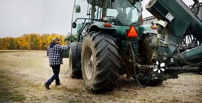 男子走向农场外的拖拉机螺旋钻图片素材