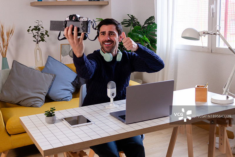 年轻男人在家用笔记本电脑和耳机录制视频博客图片素材