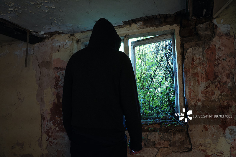 废弃房屋中背对镜头的可怕带帽身影恐怖概念图片素材