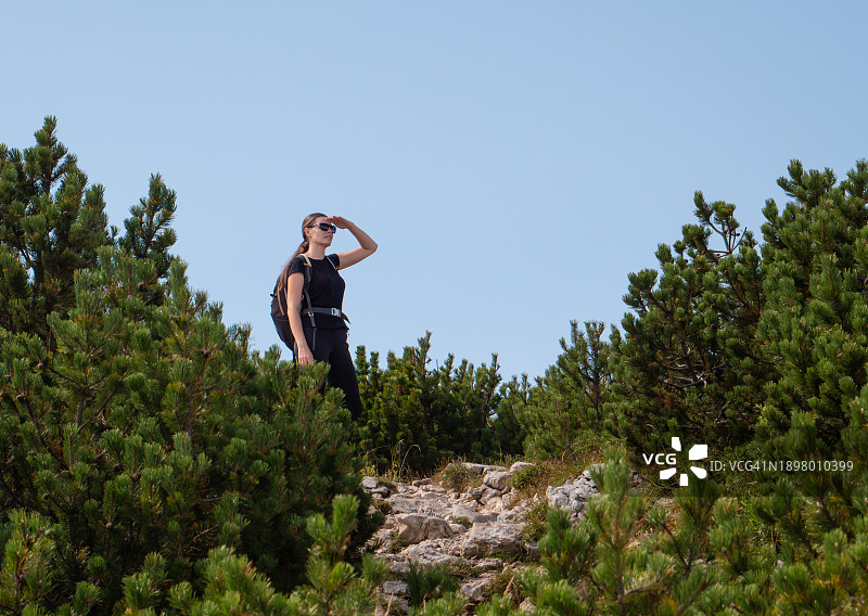 在山里四处张望的背包女孩图片素材