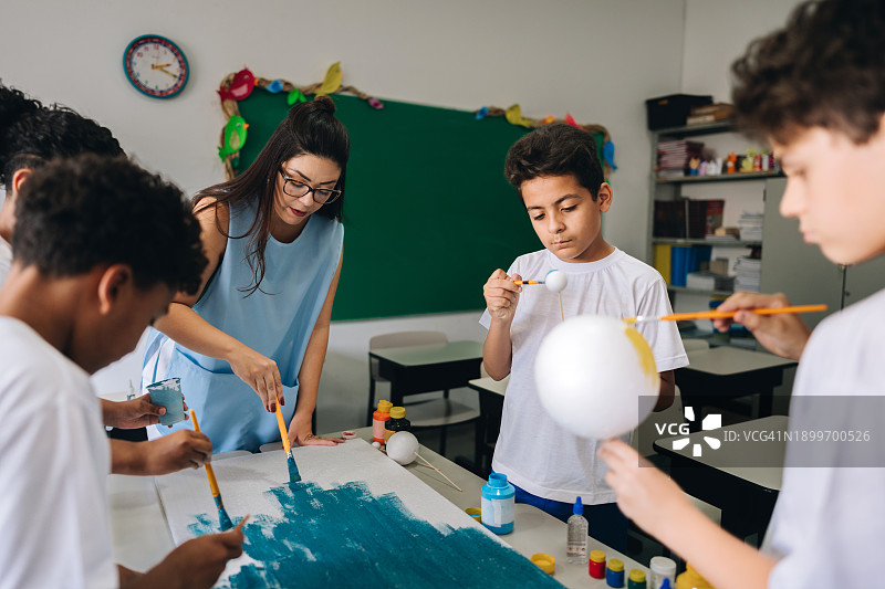 老师在教室里帮助学生们画画图片素材