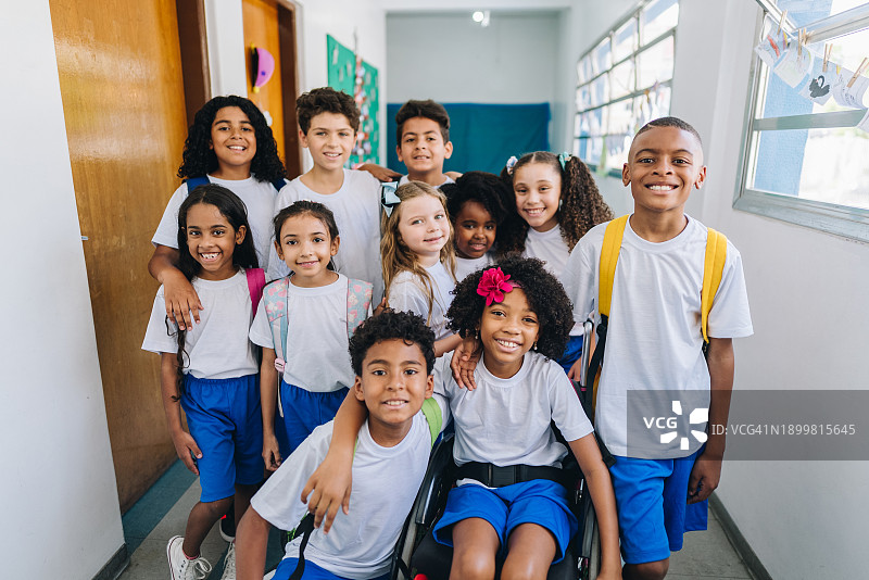 坐在轮椅上的女孩和朋友在学校走廊上的肖像图片素材
