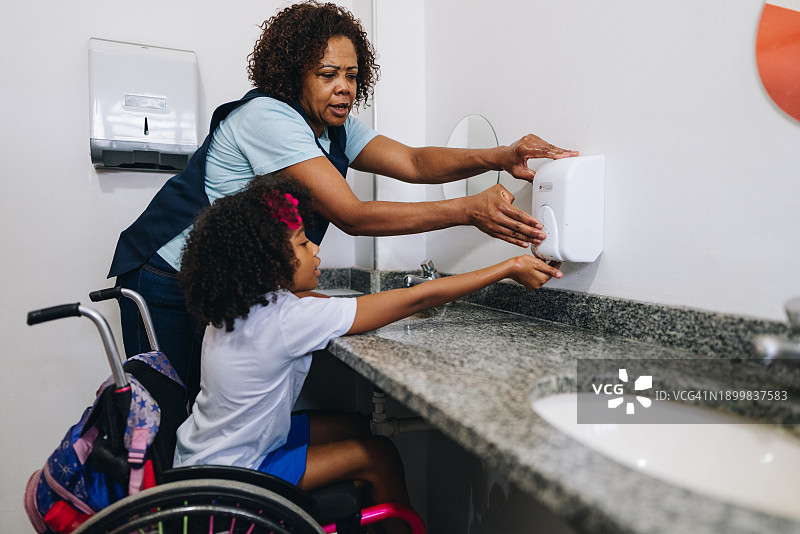 老师帮助坐轮椅的学生在学校洗手图片素材