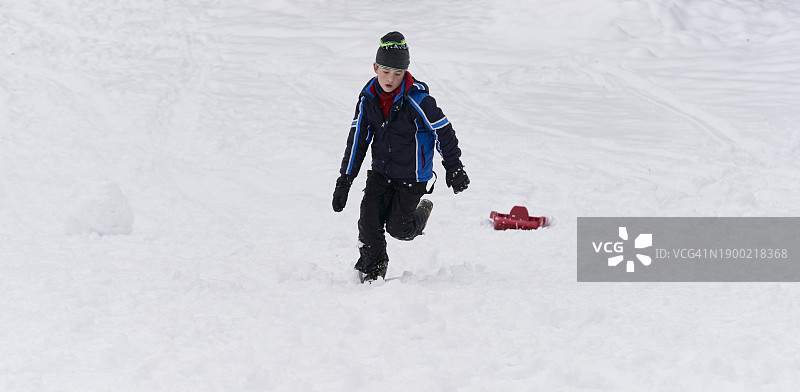 快乐的女孩穿着冬装拉着雪橇，看着镜头，享受户外冬季图片素材