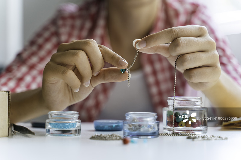 漂亮女孩在家制作宝石首饰。艺术、爱好、手工概念。图片素材