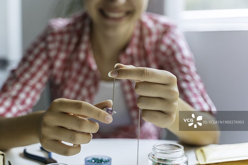 漂亮女孩在家制作宝石首饰。艺术、爱好、手工概念。图片素材