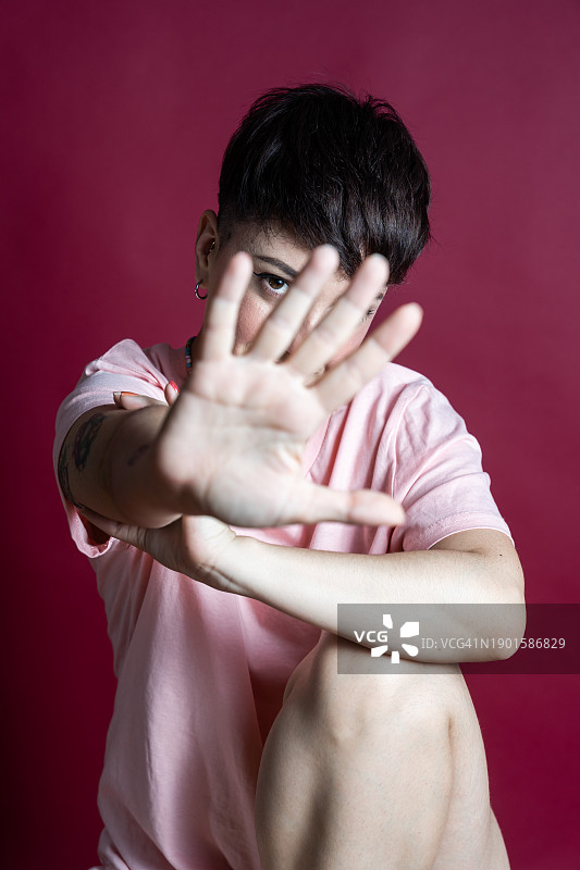 年轻女人在粉色背景上做出停止手势图片素材
