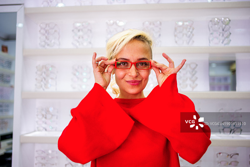 试戴眼镜看向镜头的年轻微笑女人图片素材