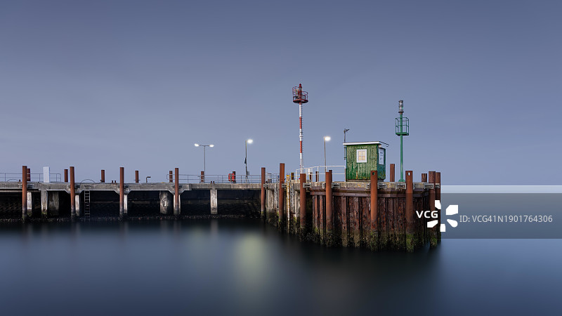 德国叙尔特岛利斯特港口入口处，蓝色时刻的灯光照亮了港口看守人的房屋的长时间曝光摄影图片素材