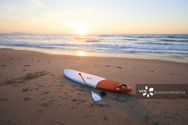 日落时分海滩上的立式桨板图片素材