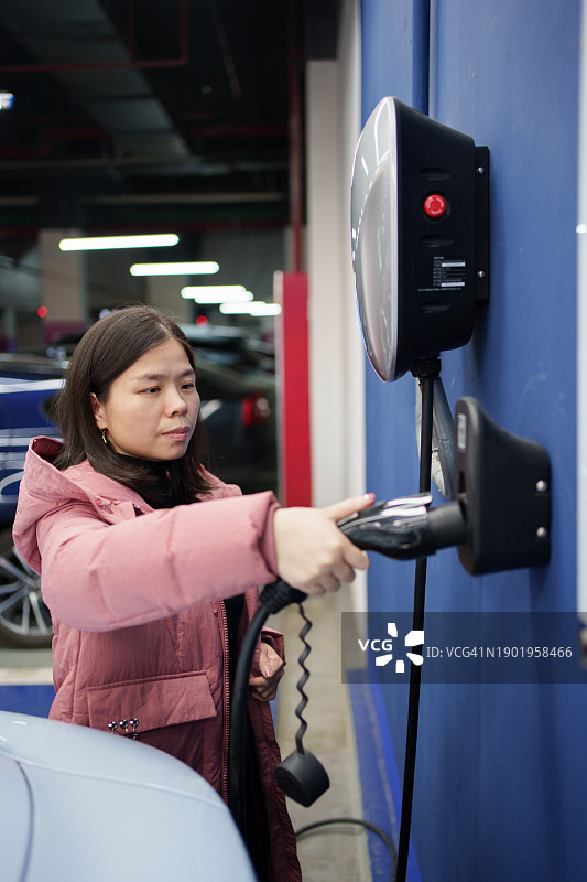 拿着电动汽车充电枪的女人图片素材