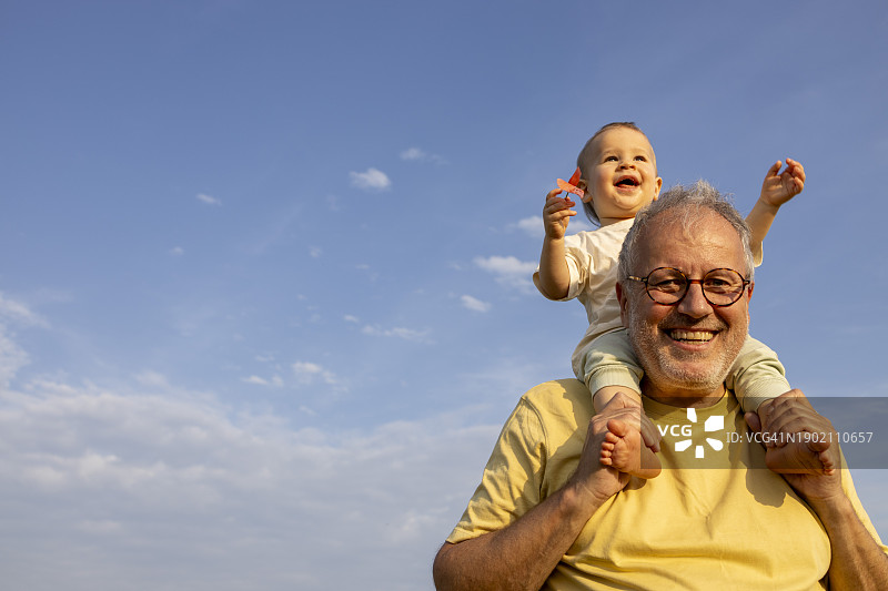 中年父亲和坐在肩膀上的男婴玩耍图片素材