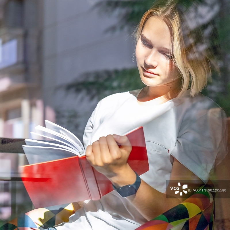 微笑的女孩在家里用红色笔记本写下新年计划和愿望图片素材