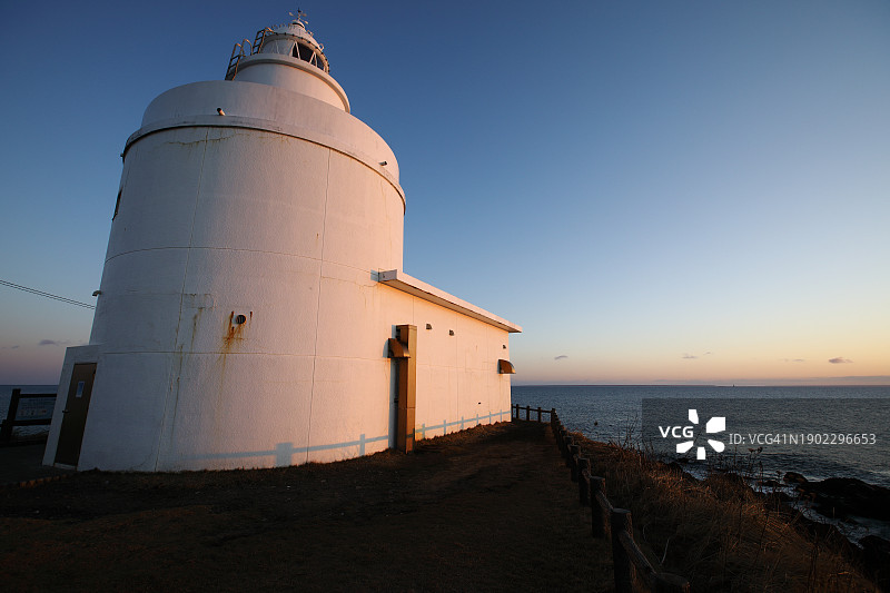黎明时分，阳光照耀下的白色灯塔广角图片素材