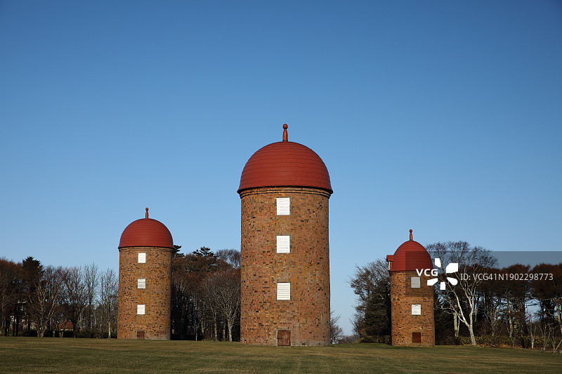 蓝天下公园树木背景中的三个红砖筒仓图片素材