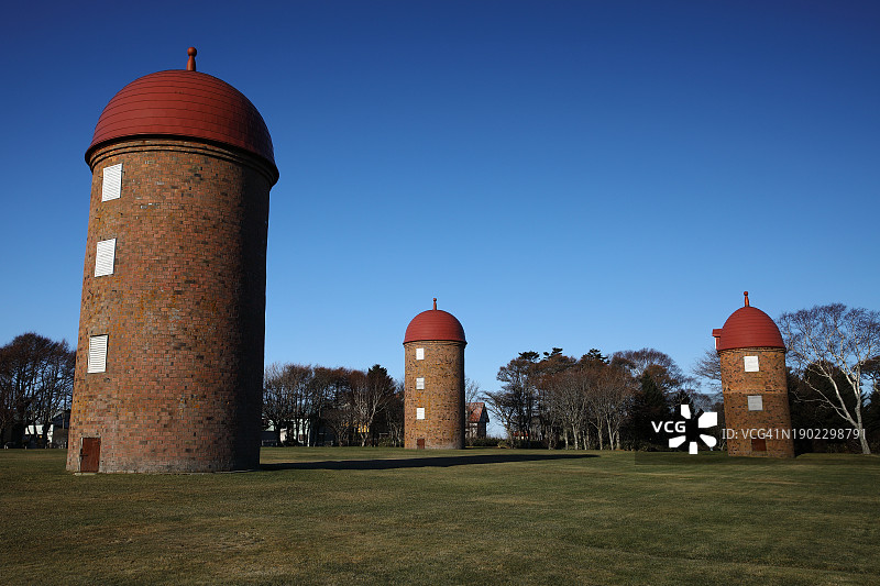 蓝天下公园树木背景中的三个红砖筒仓图片素材