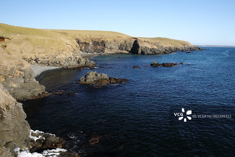 蓝色晴空下的海湾与悬崖景观图片素材