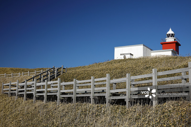 蓝天下草山上带红色塔楼的灯塔图片素材