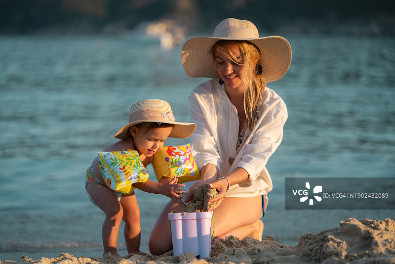 母女在沙滩上玩水桶和沙子图片素材