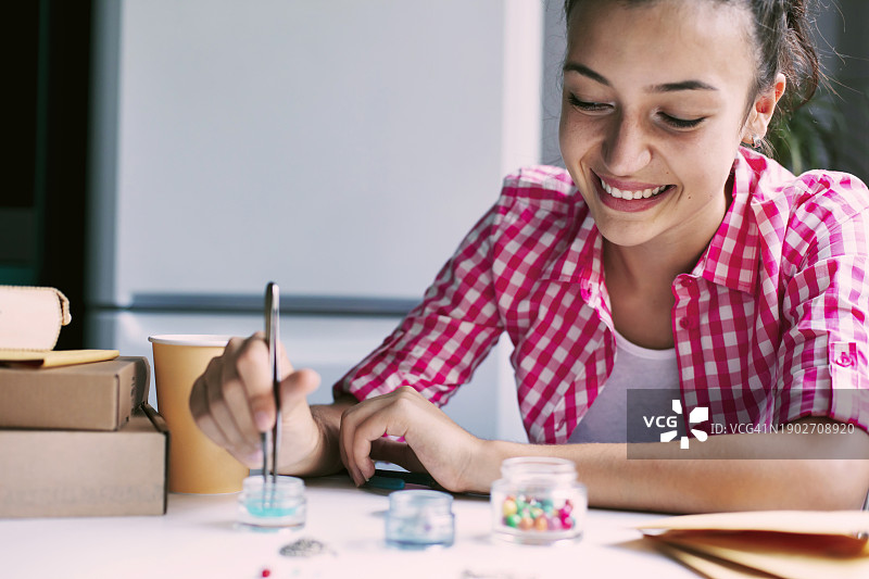 快乐微笑的少女制作手工珠宝图片素材