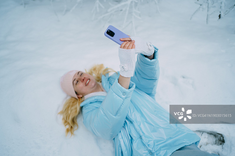 女子在森林雪地里用手机散步图片素材
