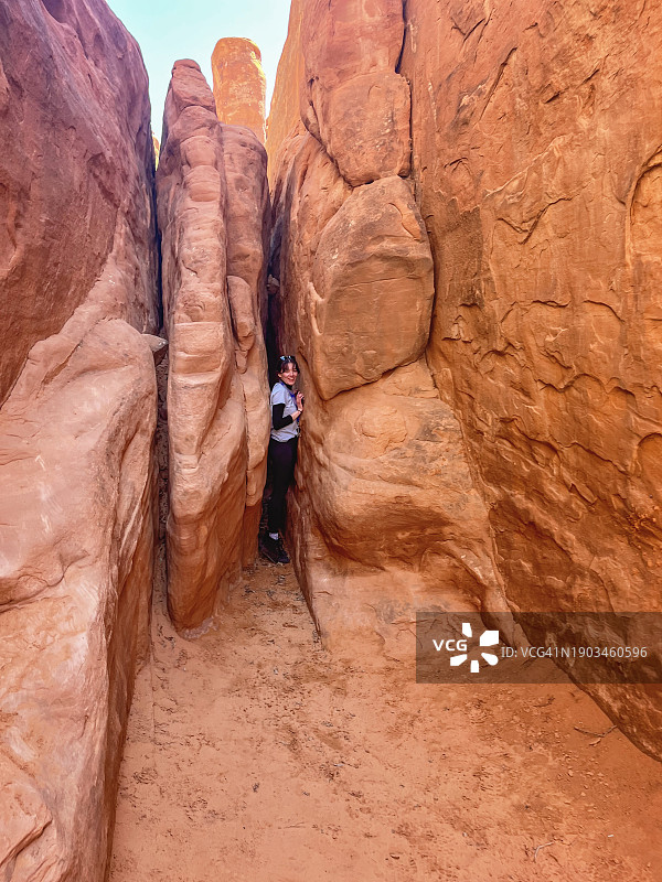 好奇的探险者：探索沙丘拱门附近的狭窄裂缝图片素材