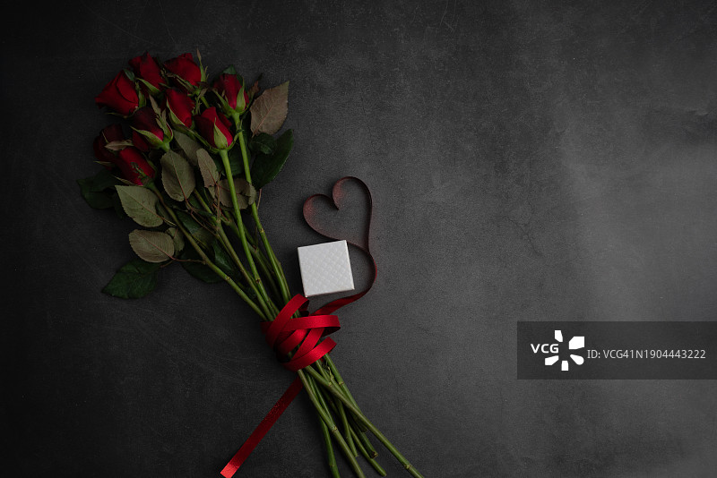 爱与情人节概念：红色玫瑰和心形丝带在黑色木质背景上图片素材