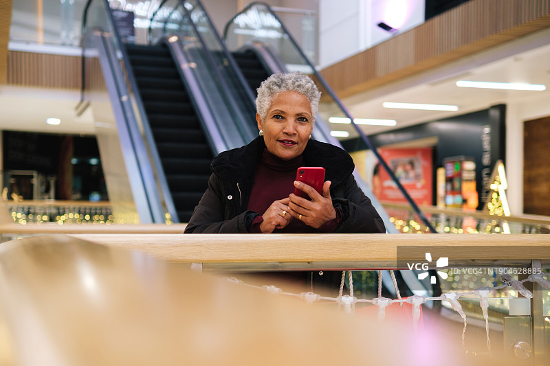 在购物中心使用智能手机的年长女人图片素材