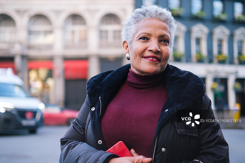 在城市环境中拿着智能手机的年长女士图片素材