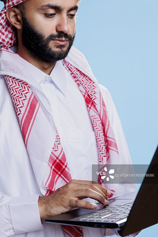 男子在蓝色背景下使用笔记本电脑图片素材