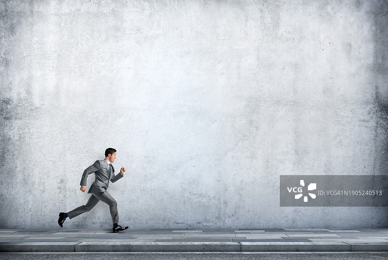 商人在水泥墙旁的人行道上奔跑图片素材