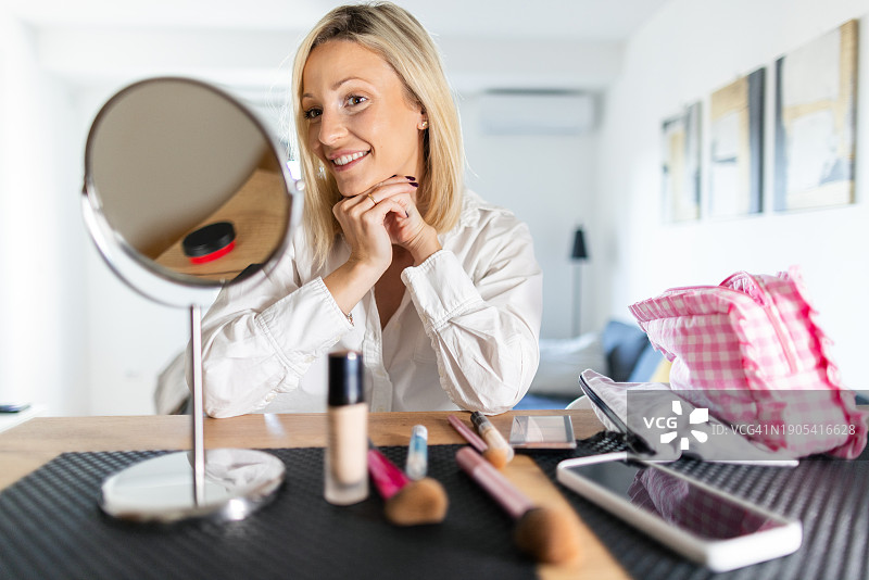 年轻漂亮的女人在客厅里化妆图片素材